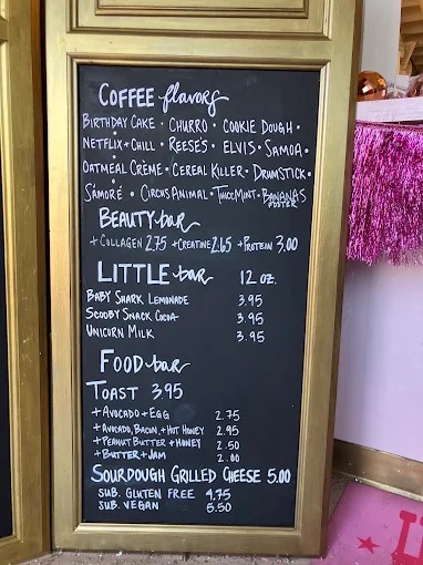 Chalkboard of coffee flavors and food next to pink tinsel at the cafe